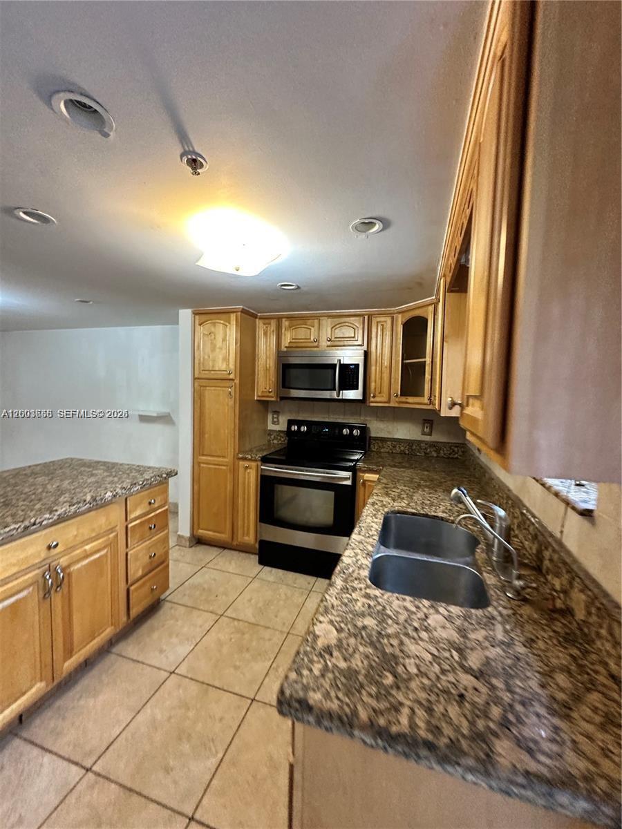 A kitchen features light wood cabinets, granite countertops, stainless steel appliances, and tile flooring — 551 NW 82nd Ave # 502, Miami FL 33126, MIAMI, FL