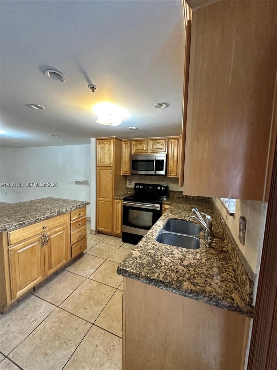 This kitchen features light wood cabinets, granite countertops, and stainless steel appliances — 551 NW 82nd Ave # 502, Miami FL 33126, MIAMI, FL