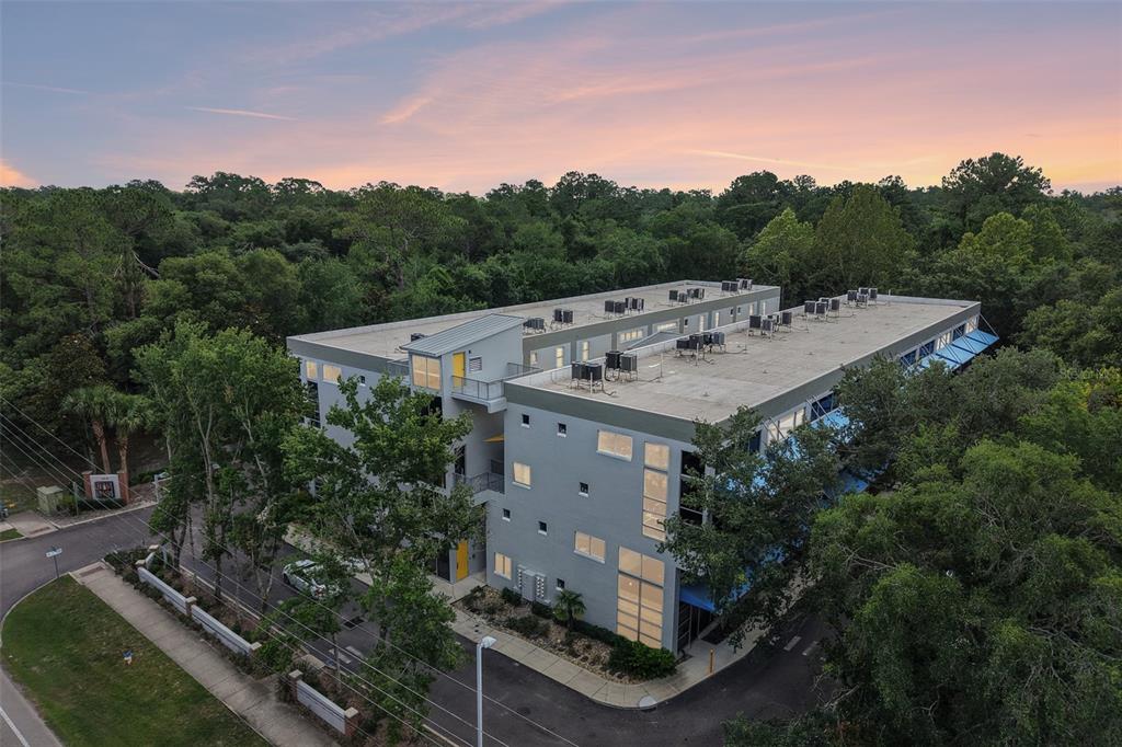 An aerial view of a modern multi-story commercial building surrounded by trees at sunset — 2515 SW 35TH PLACE UNIT 103, GAINESVILLE, FL