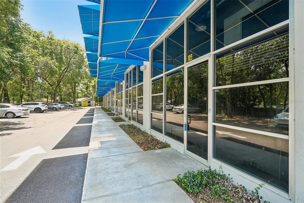 An exterior view of a commercial building with blue awnings and glass storefronts — 2515 SW 35TH PLACE UNIT 103, GAINESVILLE, FL