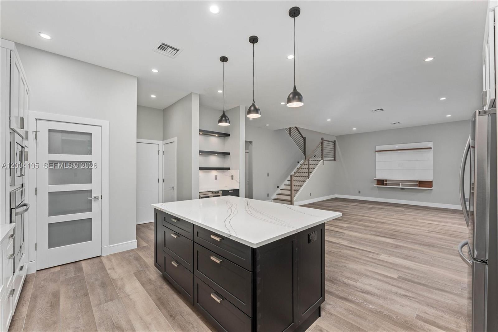 A modern kitchen features a dark island with a white countertop and three pendant lights — 2431 NE 20th Ave, Lighthouse Point FL 33064, LIGHTHOUSE POINT, FL