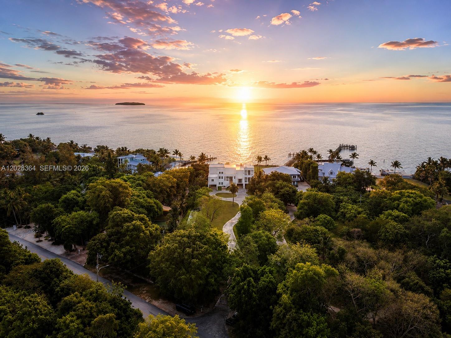 An aerial view shows a white house surrounded by trees overlooking the ocean at sunset — 89401 Old Highway, Plantation Key FL 33070, PLANTATION KEY, FL