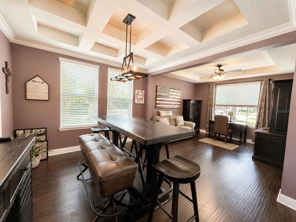 A dining room features a coffered ceiling, dark wood floors, and a large wooden table — 14301 WHITE MOSS WAY, WINTER GARDEN, FL