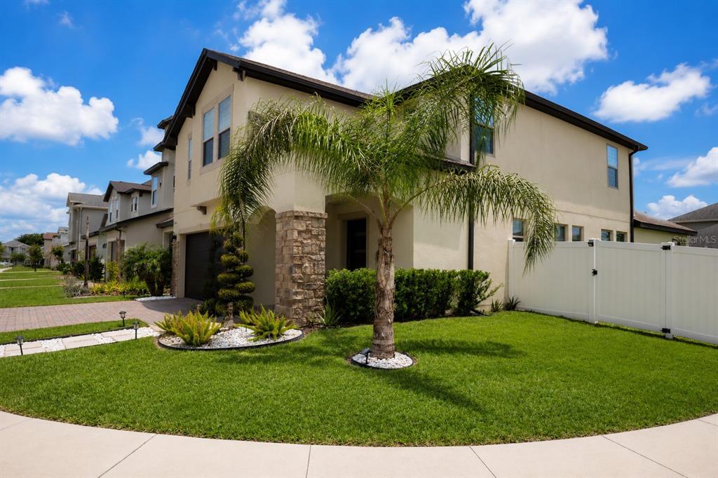 A two-story suburban house with a stone-accented entryway, a palm tree, and a white fence — 2824 NOBLE CROW DRIVE, KISSIMMEE, FL