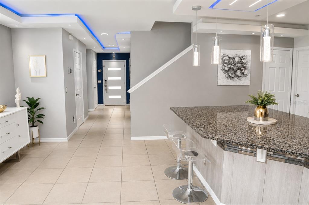 A modern kitchen with a granite island, bar stools, and blue recessed ceiling lighting — 2824 NOBLE CROW DRIVE, KISSIMMEE, FL
