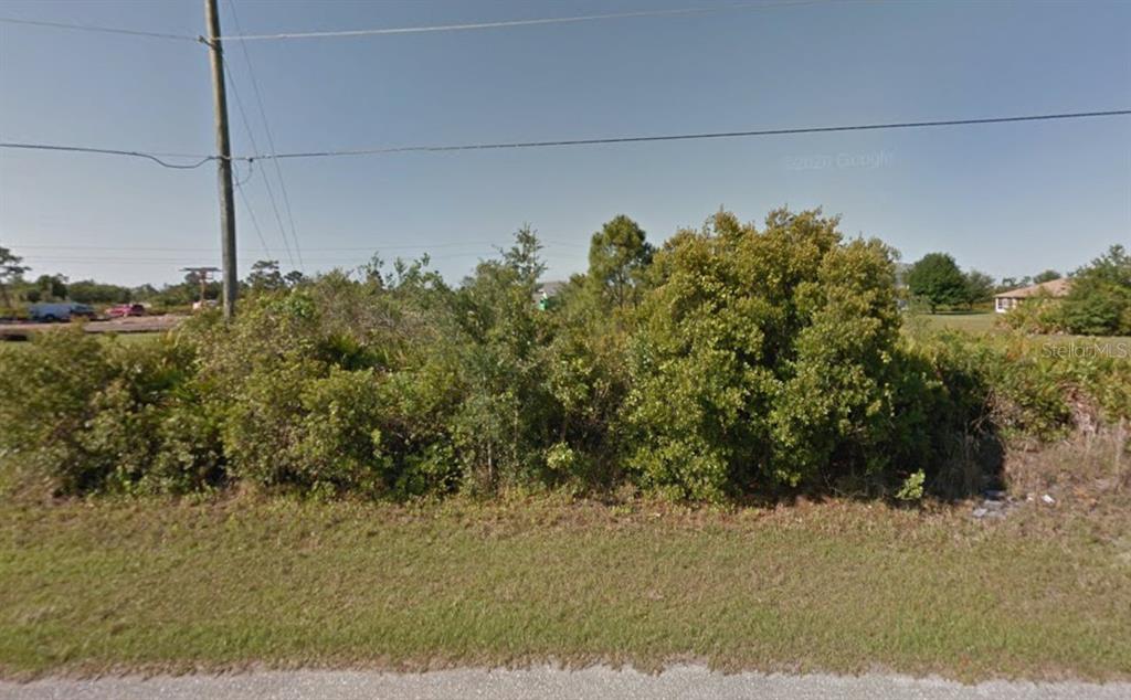 A vacant, overgrown lot with dense shrubs and trees sits along a paved road — 479 SANTIGUAY STREET, PUNTA GORDA, FL