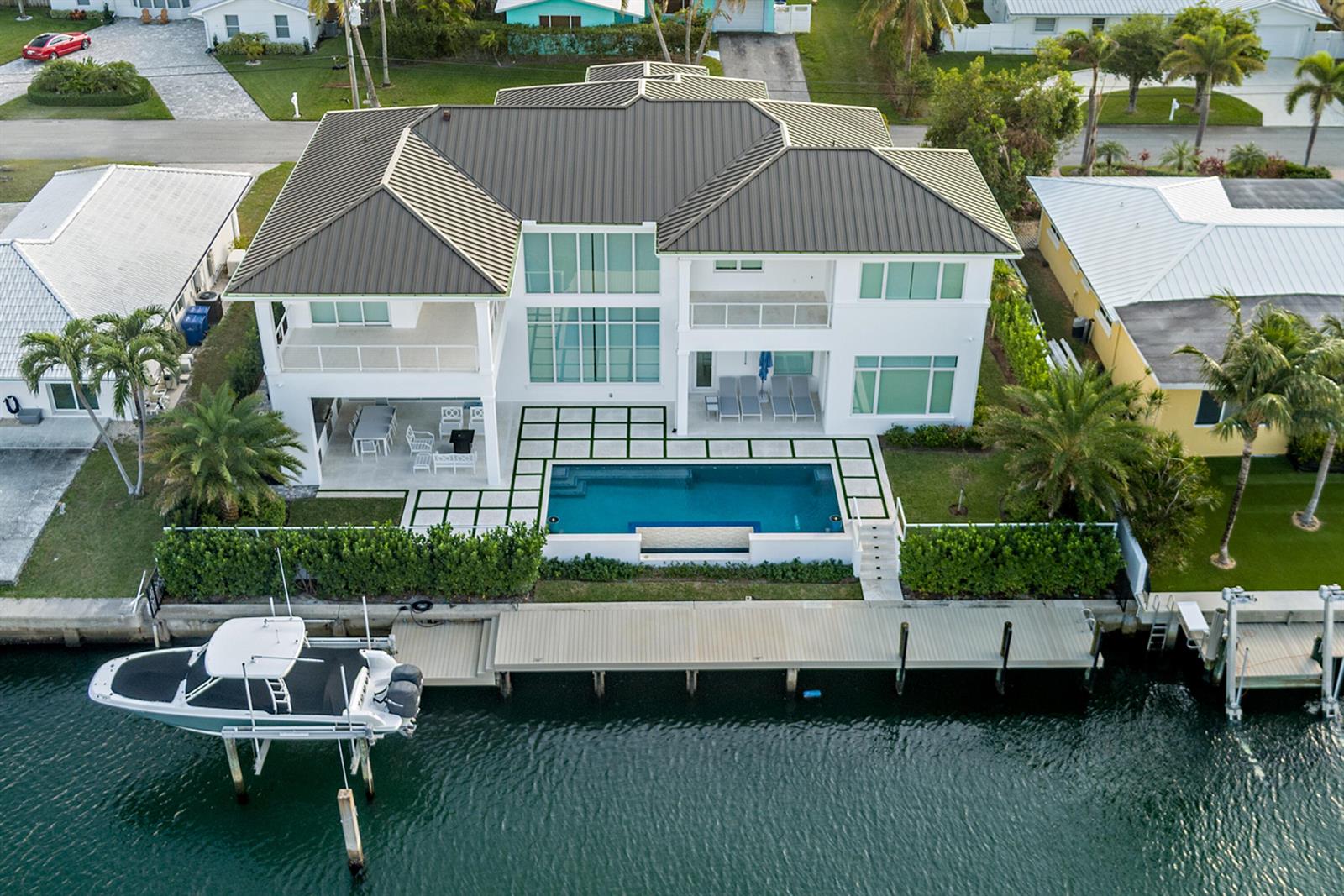 An aerial view of a white two-story house with a pool, dock, and boat lift — 1180 Bimini Lane, Singer Island FL 33404, SINGER ISLAND, FL
