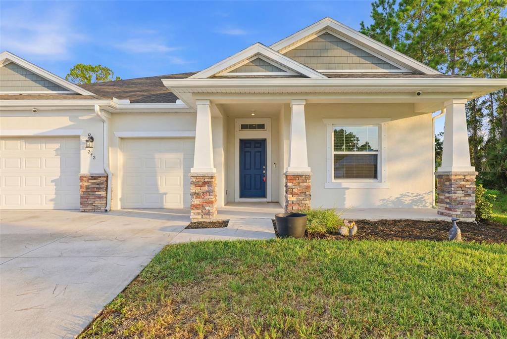 A bright, virtually staged entryway features light wood flooring, a console table, and a round mirror — 242 HERITAGE ST STREET SW, PALM BAY, FL