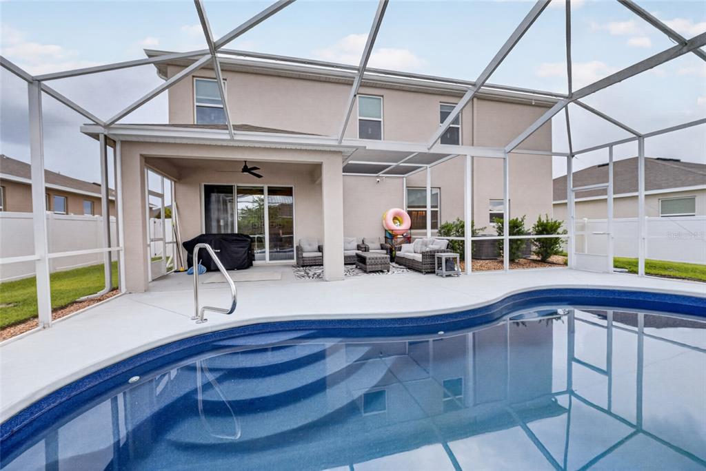 A swimming pool with a screened-in lanai and patio furniture behind a two-story house — 5859 SW 82ND LANE, OCALA, FL