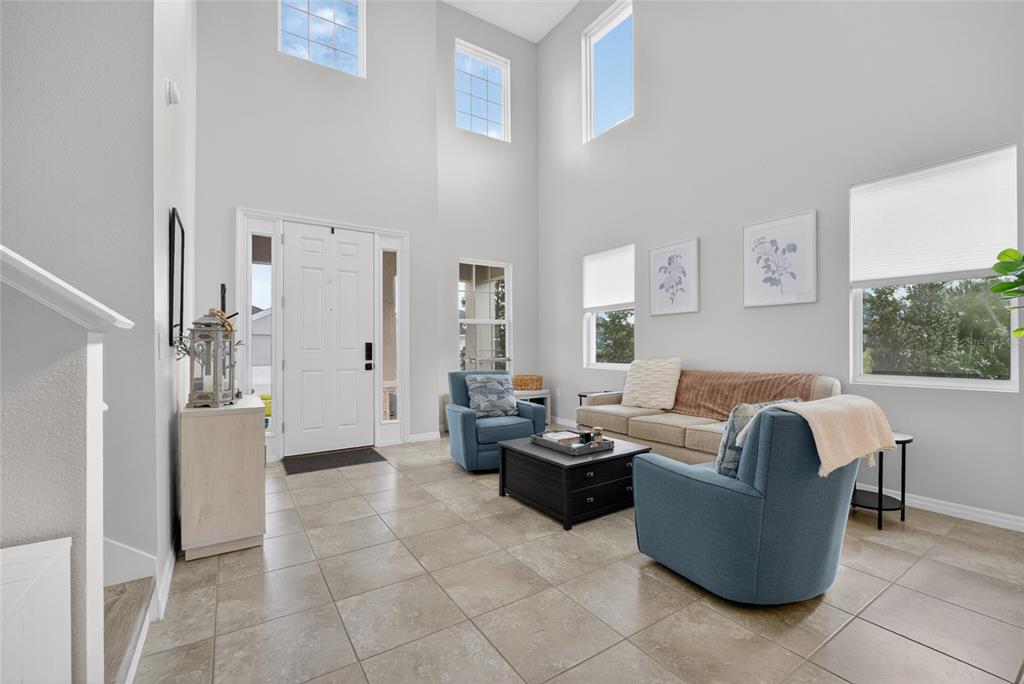 A living room with high ceilings, tile flooring, a sofa, and two blue armchairs — 5859 SW 82ND LANE, OCALA, FL