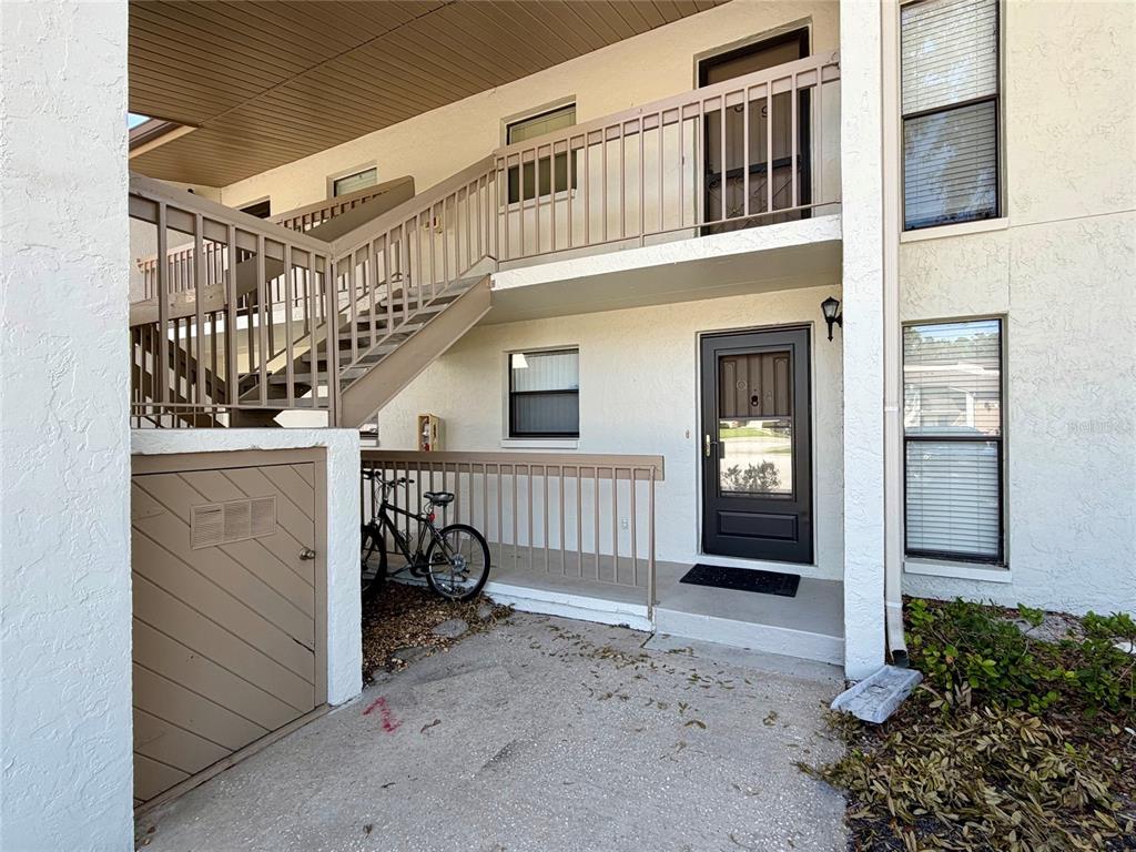 An exterior view of a two-story apartment building with a staircase and a bicycle — 1200 TARPON WOODS BOULEVARD UNIT Q4, PALM HARBOR, FL