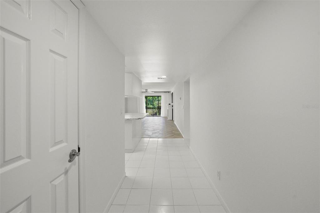 A white-tiled hallway leads to an open kitchen and a living area with balcony views — 1200 TARPON WOODS BOULEVARD UNIT Q4, PALM HARBOR, FL