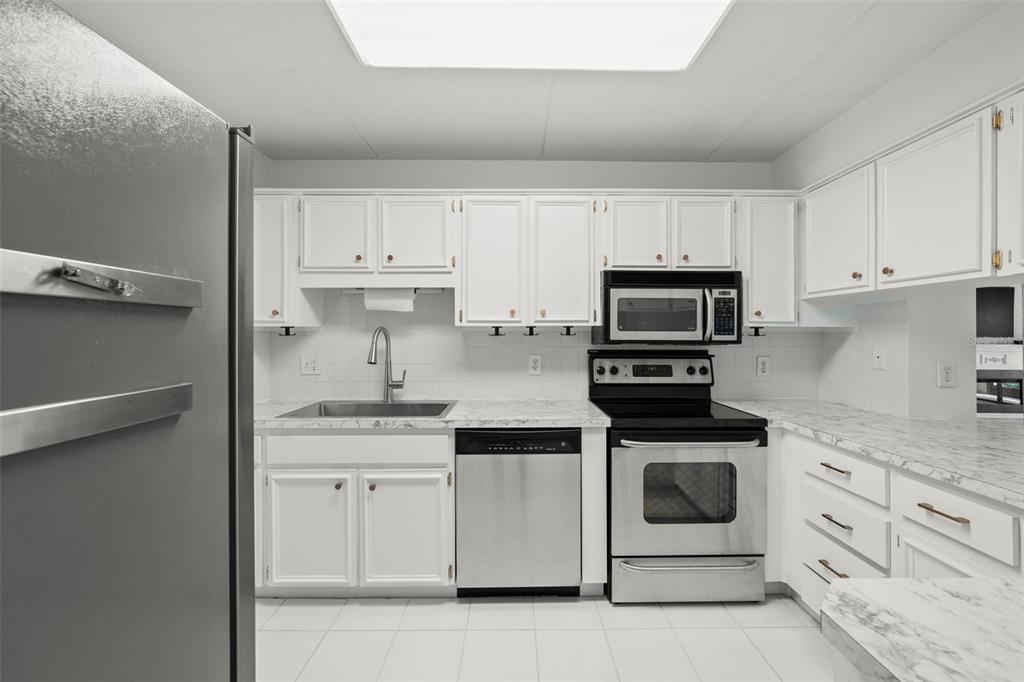 A kitchen features white cabinets, stainless steel appliances, and white marble-patterned countertops — 1200 TARPON WOODS BOULEVARD UNIT Q4, PALM HARBOR, FL
