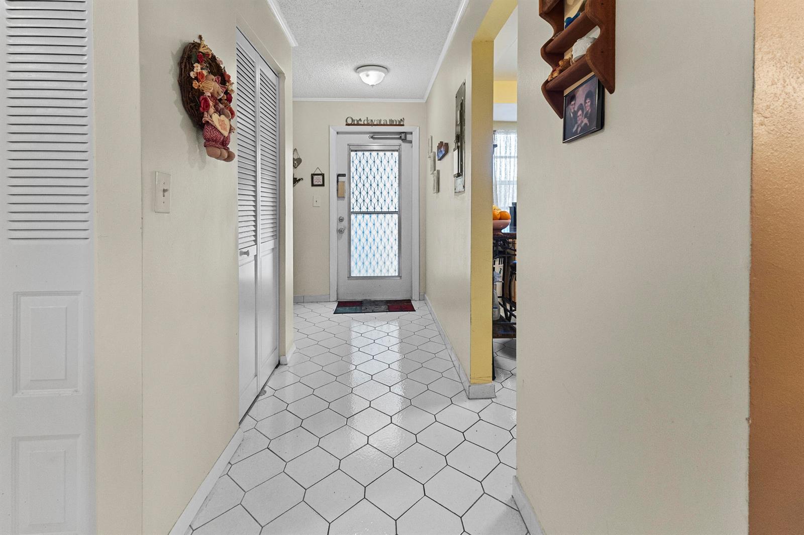 A hallway with white hexagonal floor tiles leads to an exterior door with a screen — 1470 NW 80th Avenue # 204, Margate FL 33063, MARGATE, FL