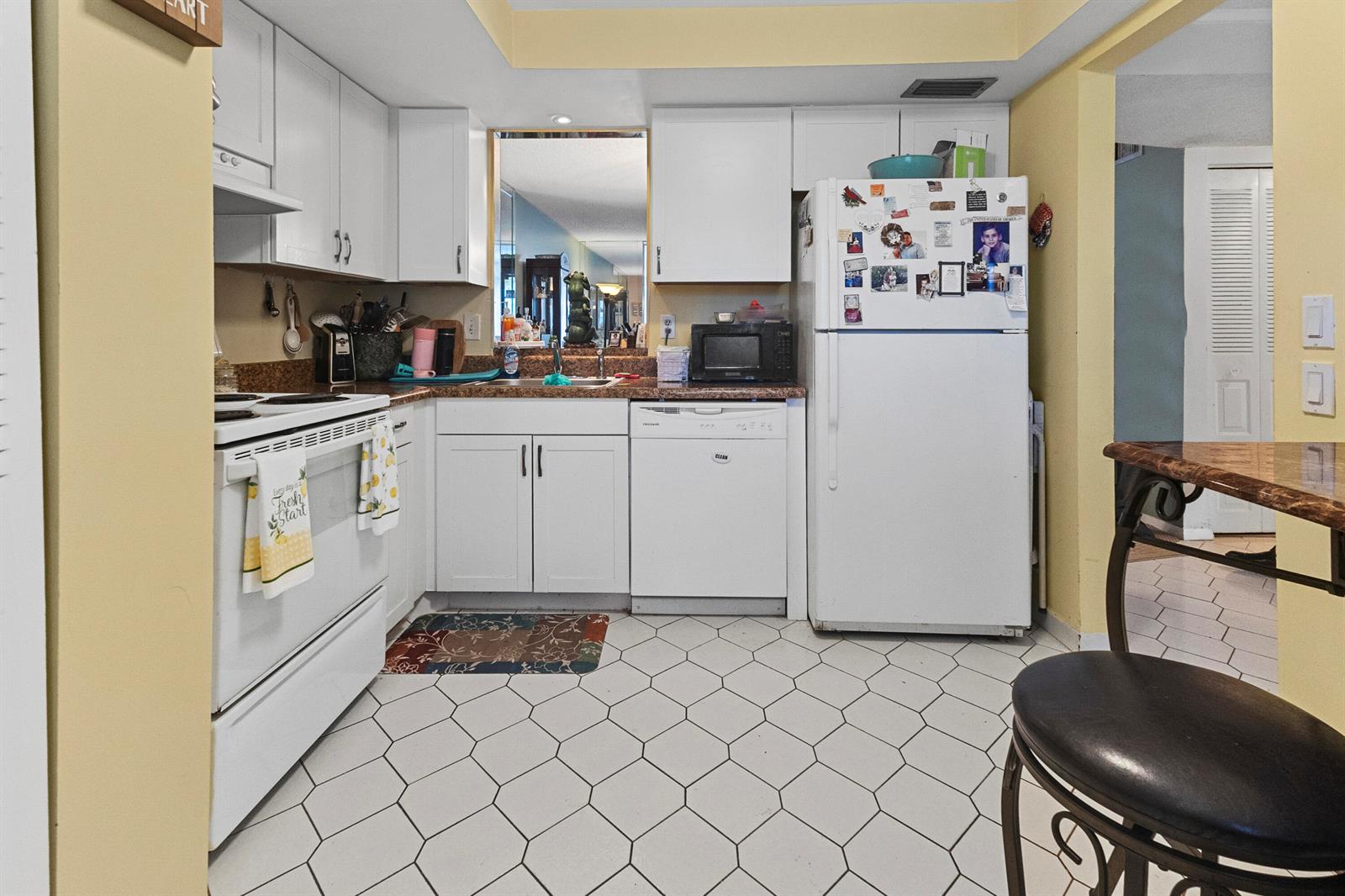 A kitchen features white cabinets, white appliances, a tiled floor, and yellow walls — 1470 NW 80th Avenue # 204, Margate FL 33063, MARGATE, FL