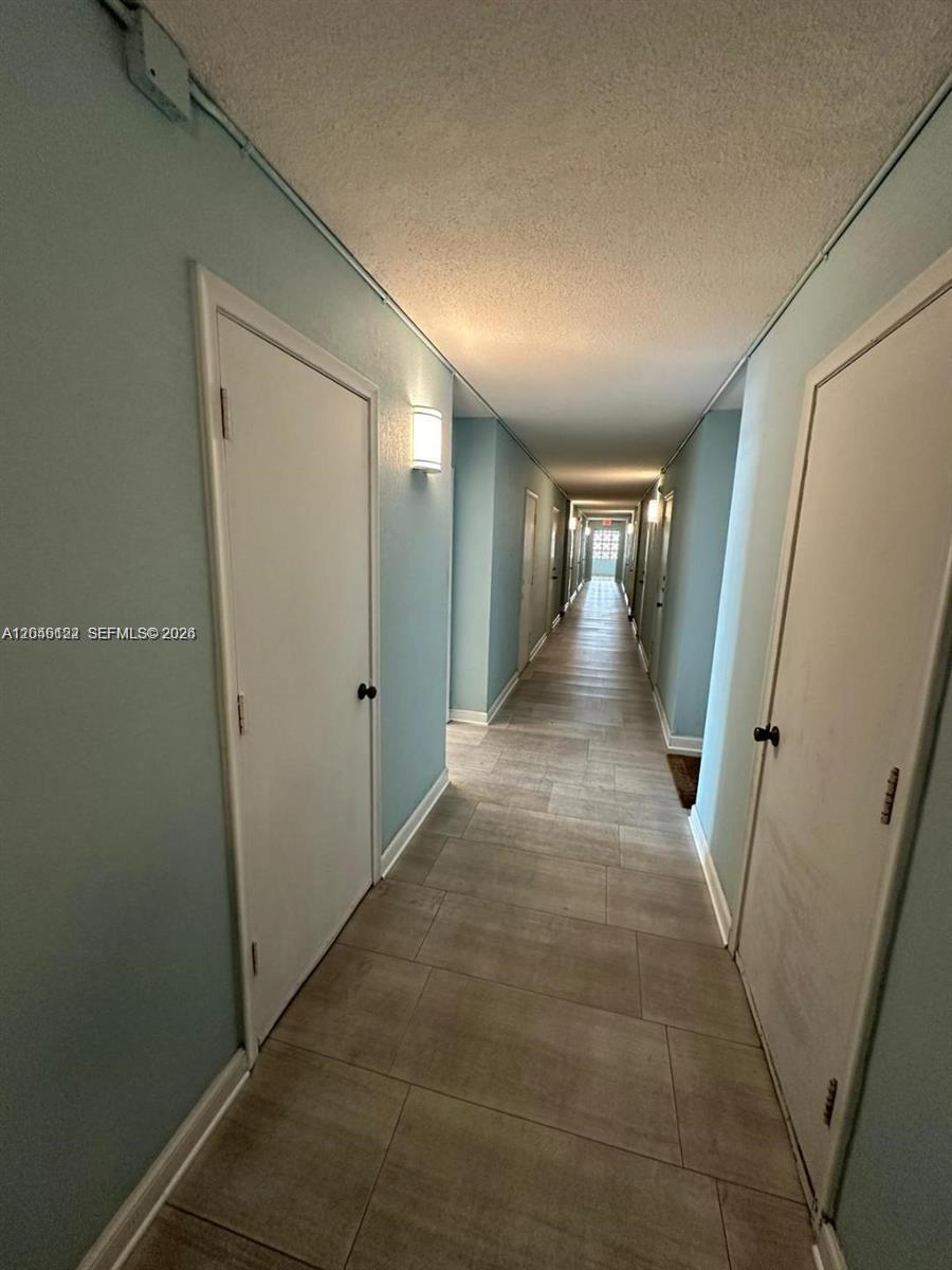A long, narrow hallway features light blue walls, white doors, and light-colored tile flooring — HALLANDALE BEACH, FL