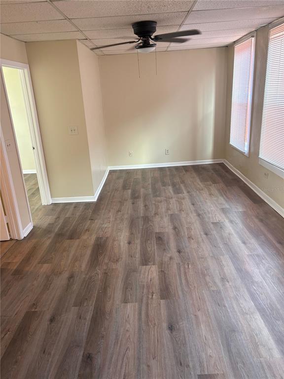 An empty room features wood-look flooring, beige walls, a ceiling fan, and two windows — 111 S NEWPORT AVENUE UNIT 15, TAMPA, FL