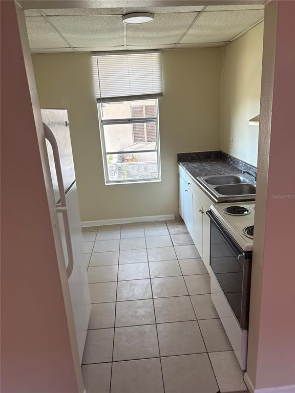 A galley-style kitchen features white appliances, light-colored tile flooring, and a single window — 111 S NEWPORT AVENUE UNIT 15, TAMPA, FL
