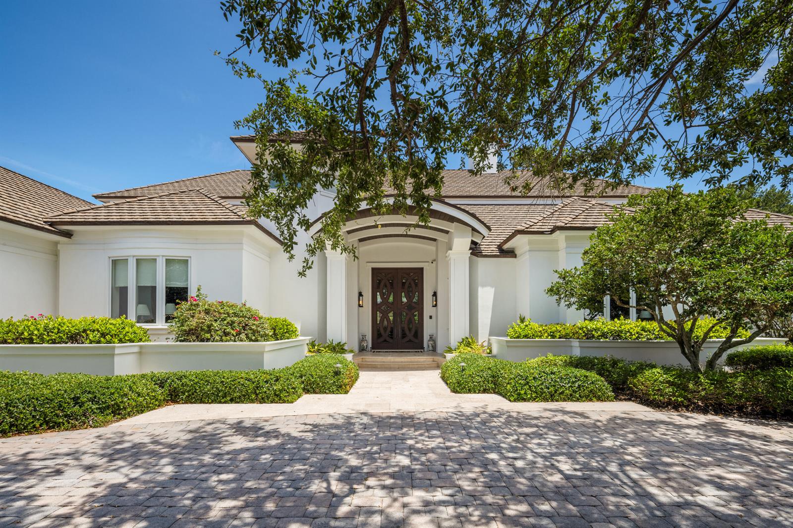 The exterior of a white house features a dark wood double door and arched entryway — 17965 SE Village Circle, Jupiter FL 33469, JUPITER, FL