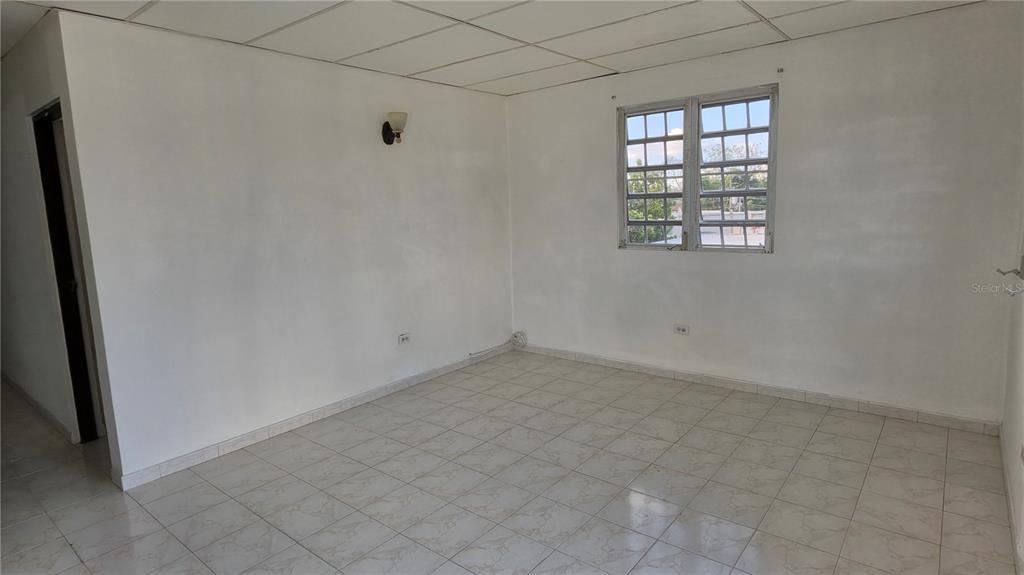 An empty room with white walls, a tiled floor, a drop ceiling, and a window — CALLE 6, G-27 URB FRANCISCO OLLER UNIT 2, BAYAMON, PR