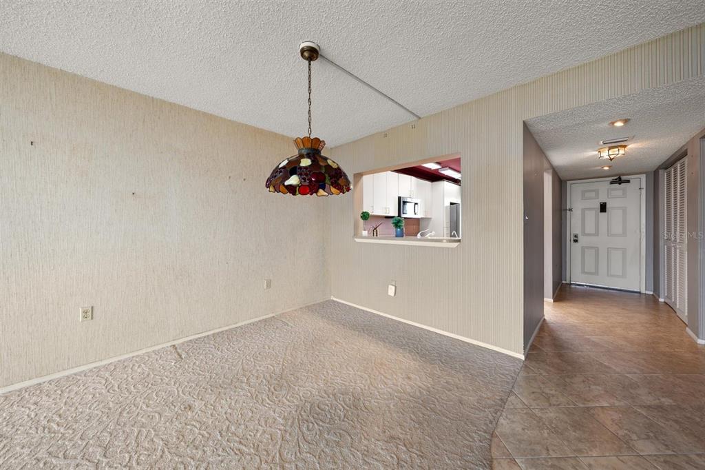 A dining area with carpet, a stained-glass pendant light, and a pass-through to the kitchen — 1250 GULF BOULEVARD UNIT 706, CLEARWATER BEACH, FL