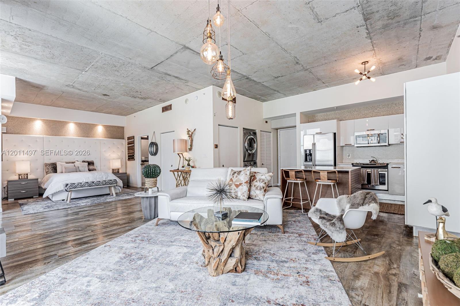 An open-concept studio apartment features a bedroom, living area, and kitchen with concrete ceilings — 133 NE 2nd Ave # 1208, Miami FL 33132, MIAMI, FL