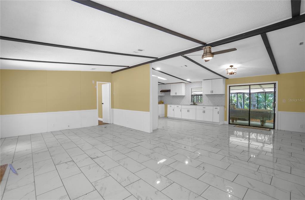 An open-concept living area features white tile flooring, yellow walls, and a white kitchen — 6550 SE DEBRA AVENUE, INGLIS, FL