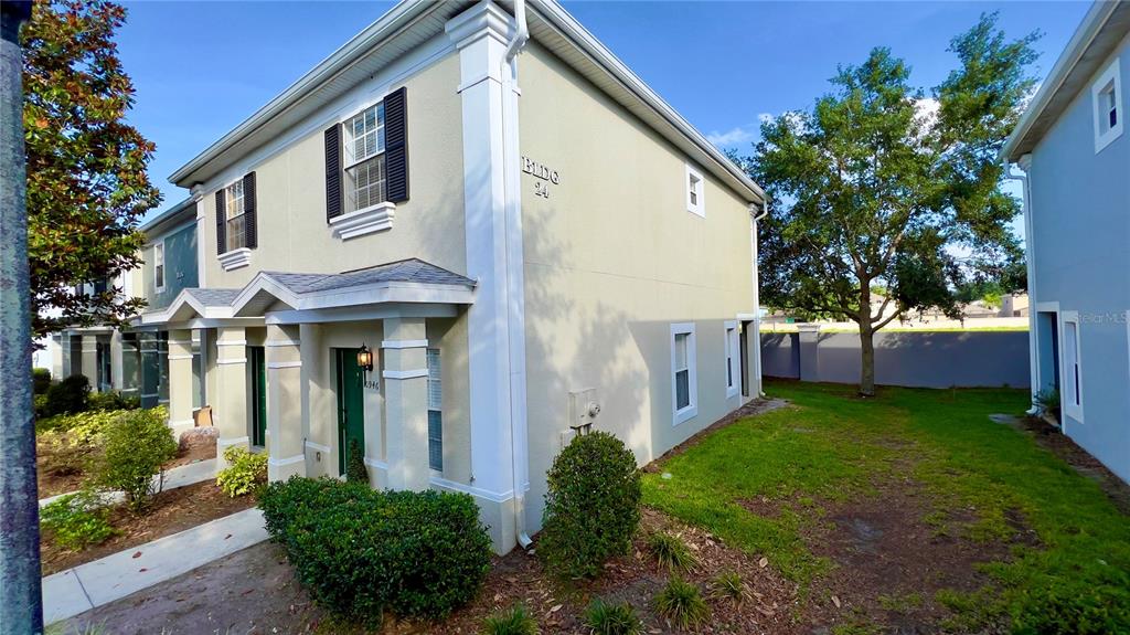 A two-story tan building with dark shutters and a green door in a residential complex — 10946 SAVANNAH WOOD DRIVE UNIT 147, ORLANDO, FL