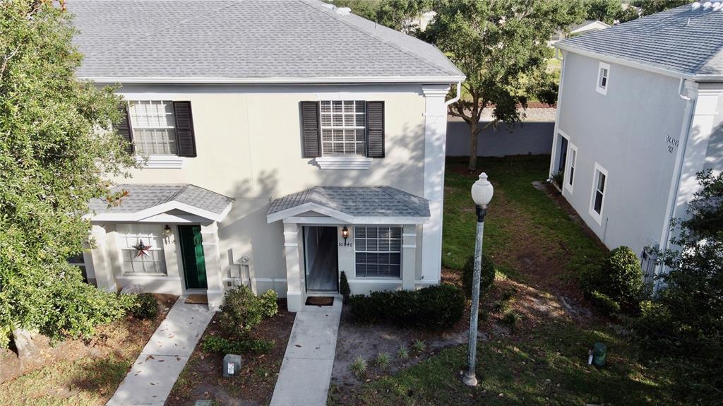 An aerial view shows the exterior of two adjacent two-story townhomes with light-colored siding — 10946 SAVANNAH WOOD DRIVE UNIT 147, ORLANDO, FL