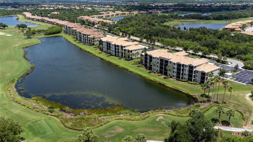 An aerial view shows multi-story apartment buildings situated along a large pond and golf course — 7005 RIVER HAMMOCK DRIVE UNIT 202, BRADENTON, FL