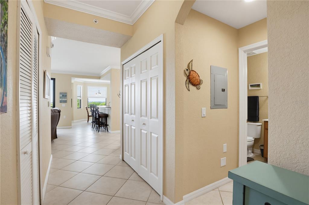 A hallway with tile flooring leads to an open-concept kitchen and living area — 7005 RIVER HAMMOCK DRIVE UNIT 202, BRADENTON, FL