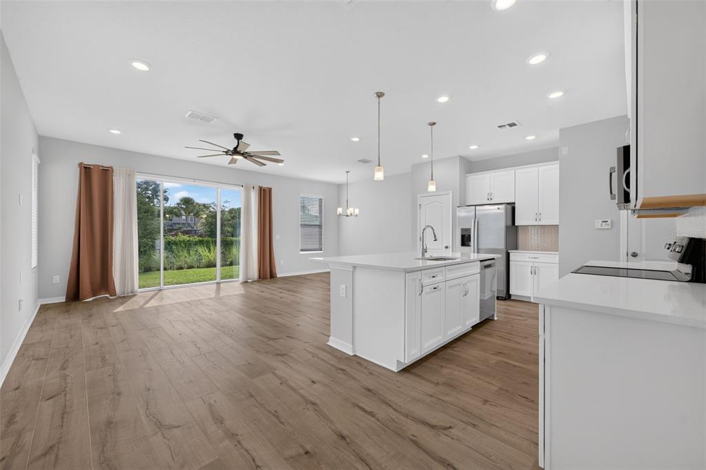 An open-concept kitchen and living area with white cabinetry, a central island, and wood flooring — 1703 TERRAPIN ROAD, OCOEE, FL