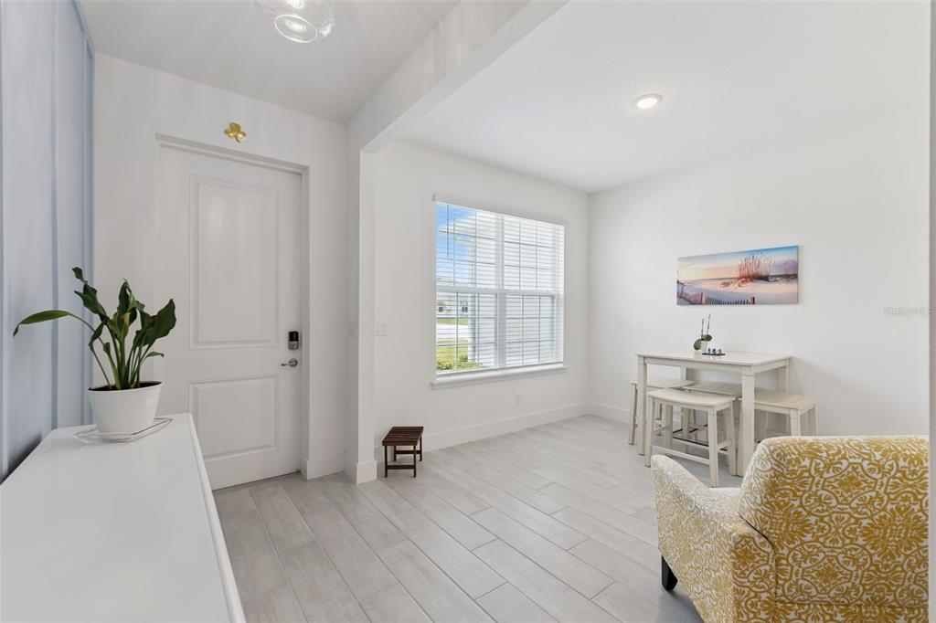 A bright entryway features white walls, light tile flooring, a front door, and a dining set — 3093 ADRIAN DR, ORMOND BEACH, FL