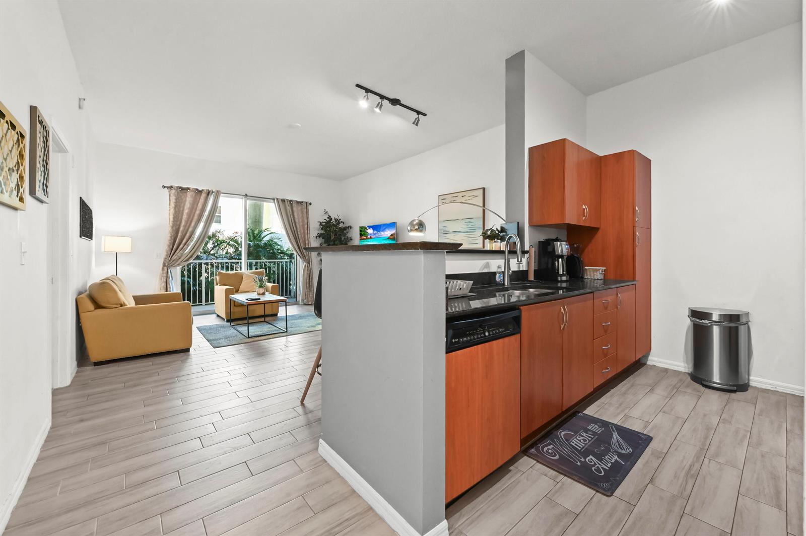 An open-concept kitchen with wood cabinets and a living area with a balcony view — 804 E Windward Way # 122, Lantana FL 33462, LANTANA, FL