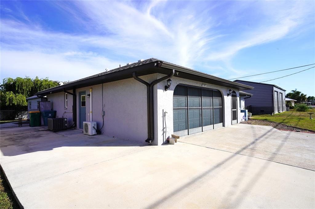 A side view of a house exterior featuring a concrete driveway and a garage door — 19891 MIDWAY BOULEVARD, PORT CHARLOTTE, FL