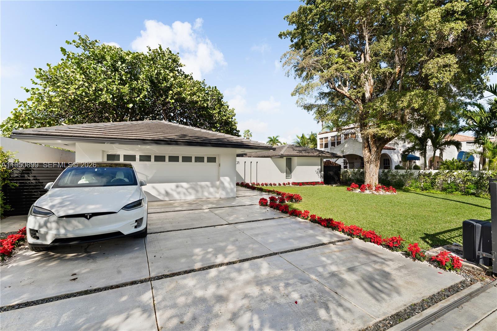 A white Tesla is parked on a concrete driveway in front of a modern house — 1071 NE 83rd St, Miami FL 33138, MIAMI, FL