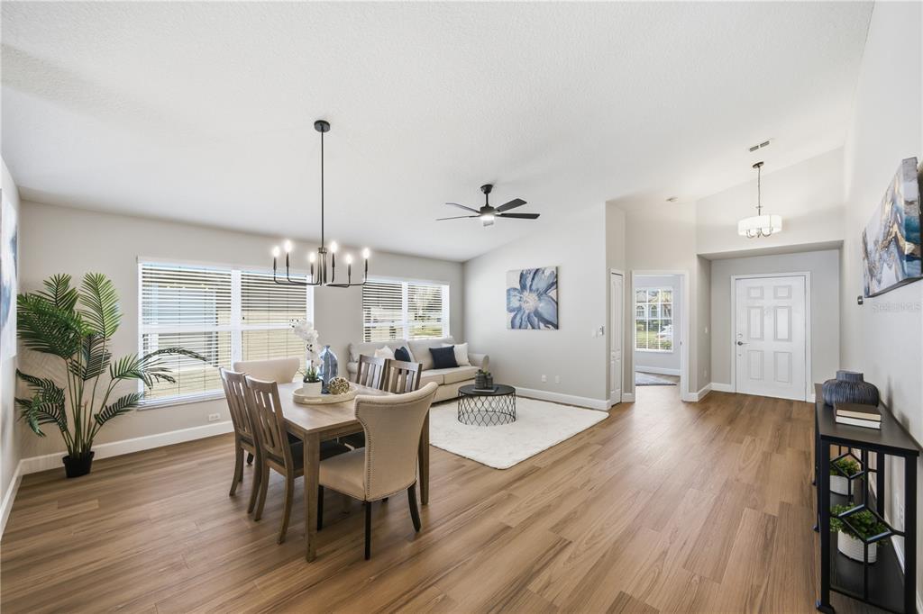 An open-concept dining and living area features light wood flooring, a chandelier, and neutral walls — 2946 STAR GRASS POINT, OVIEDO, FL