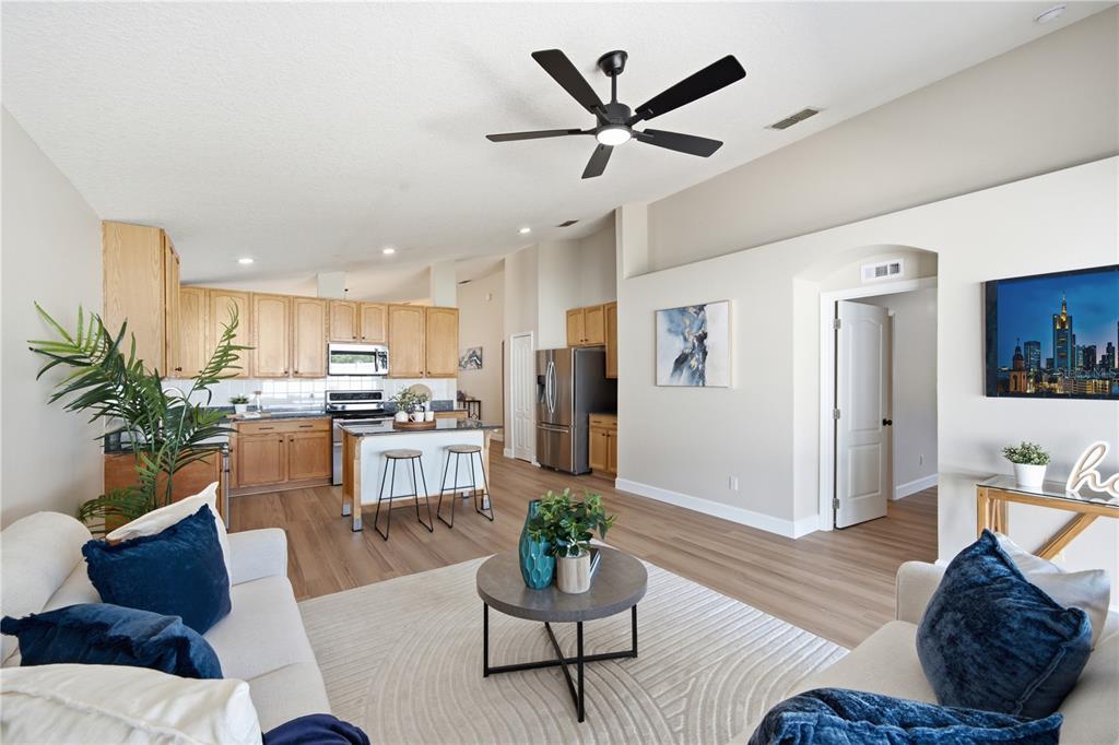 An open-concept living room and kitchen featuring light wood cabinetry, wood-look flooring, and a ceiling fan — 2946 STAR GRASS POINT, OVIEDO, FL