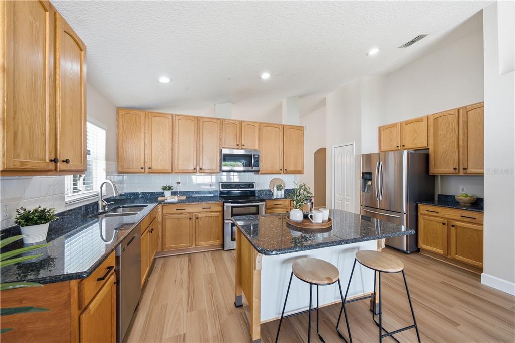 A kitchen features oak cabinets, dark granite countertops, a center island, and stainless steel appliances — 2946 STAR GRASS POINT, OVIEDO, FL