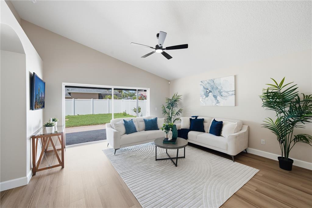 A bright living room features a vaulted ceiling, white sofas, a round table, and sliding doors — 2946 STAR GRASS POINT, OVIEDO, FL