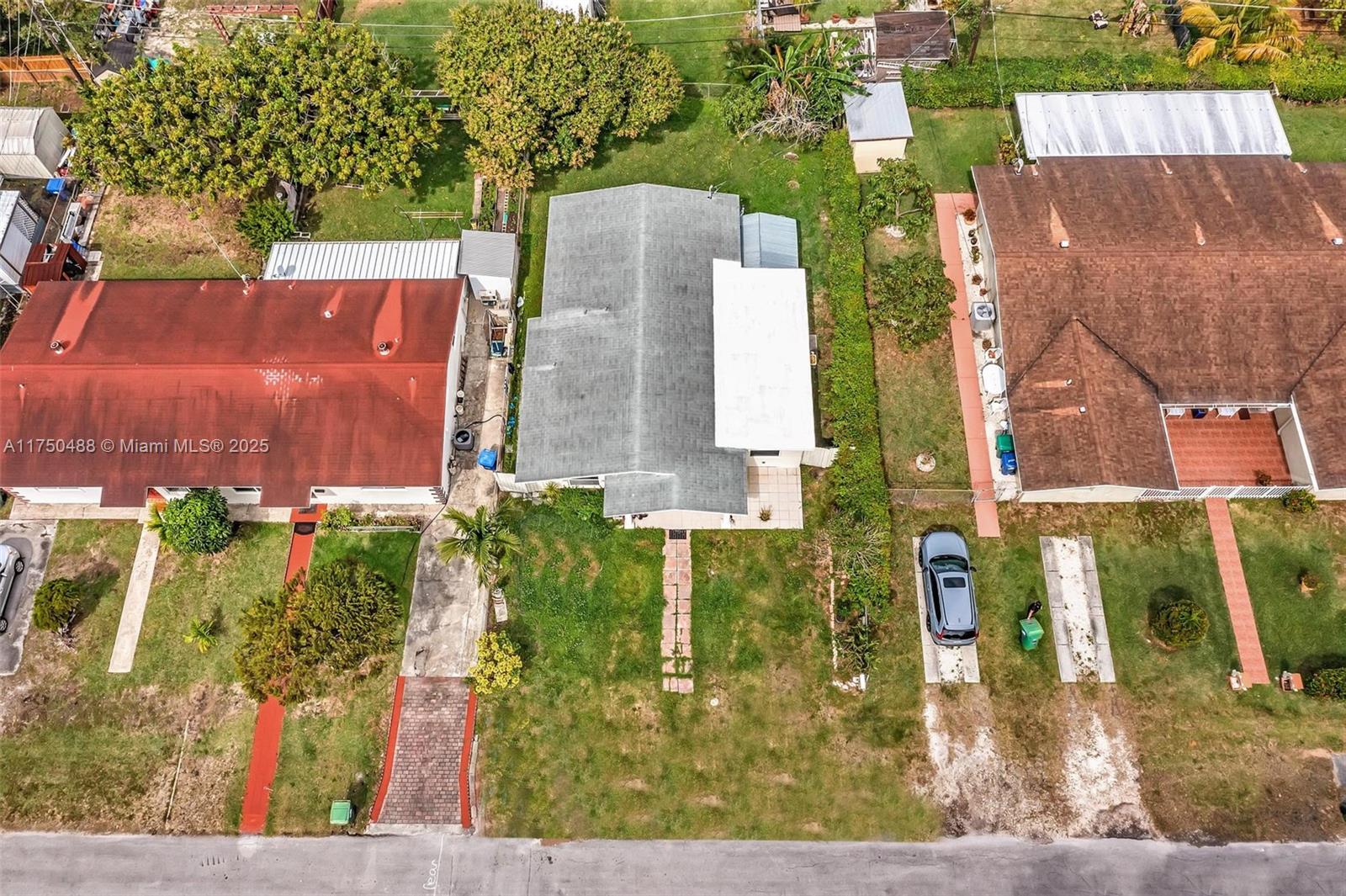 An aerial view shows three residential houses with driveways and lawns on a suburban street — 2631 NE 214th St, Miami FL 33180, MIAMI, FL
