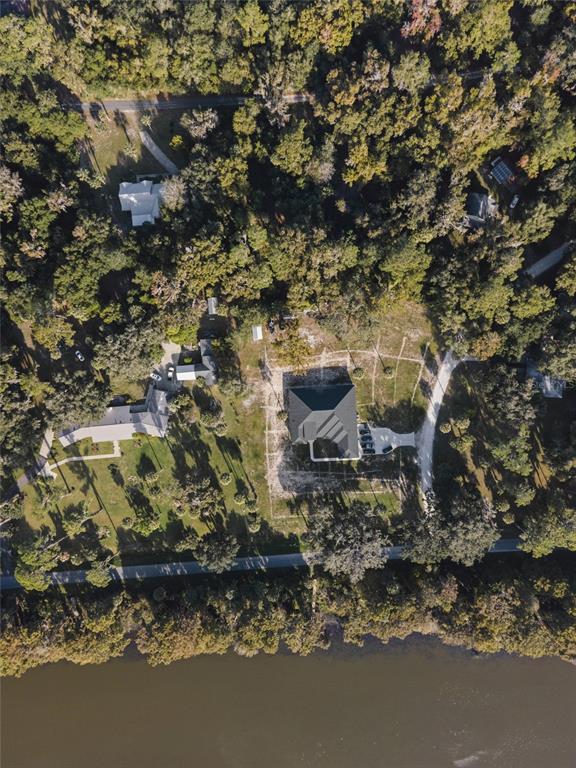 Aerial view of a house with a dark roof situated on a wooded waterfront lot — 6809 SE 14TH LANE, GAINESVILLE, FL