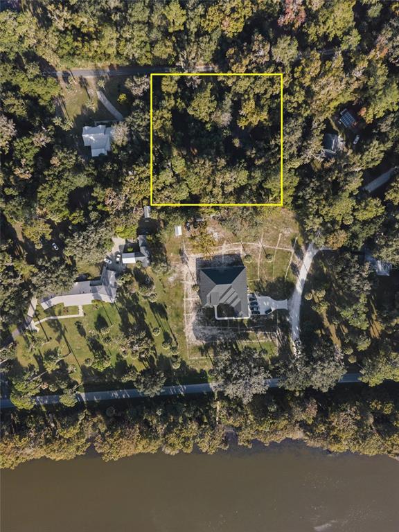An aerial view shows a wooded lot outlined in yellow near a house and river — 6809 SE 14TH LANE, GAINESVILLE, FL