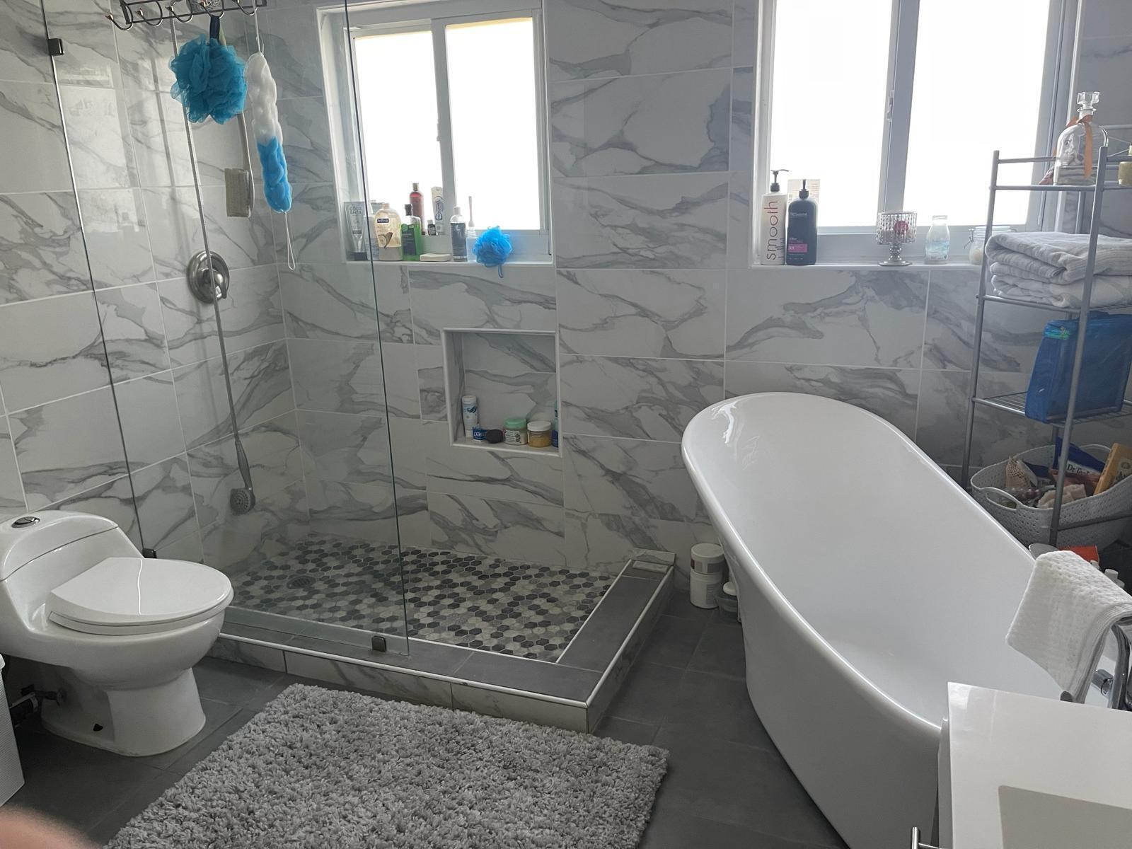 A bathroom features a glass-enclosed shower, a freestanding tub, and marble-patterned tile walls — 6807 Via Regina # 1, Boca Raton FL 33433, BOCA RATON, FL