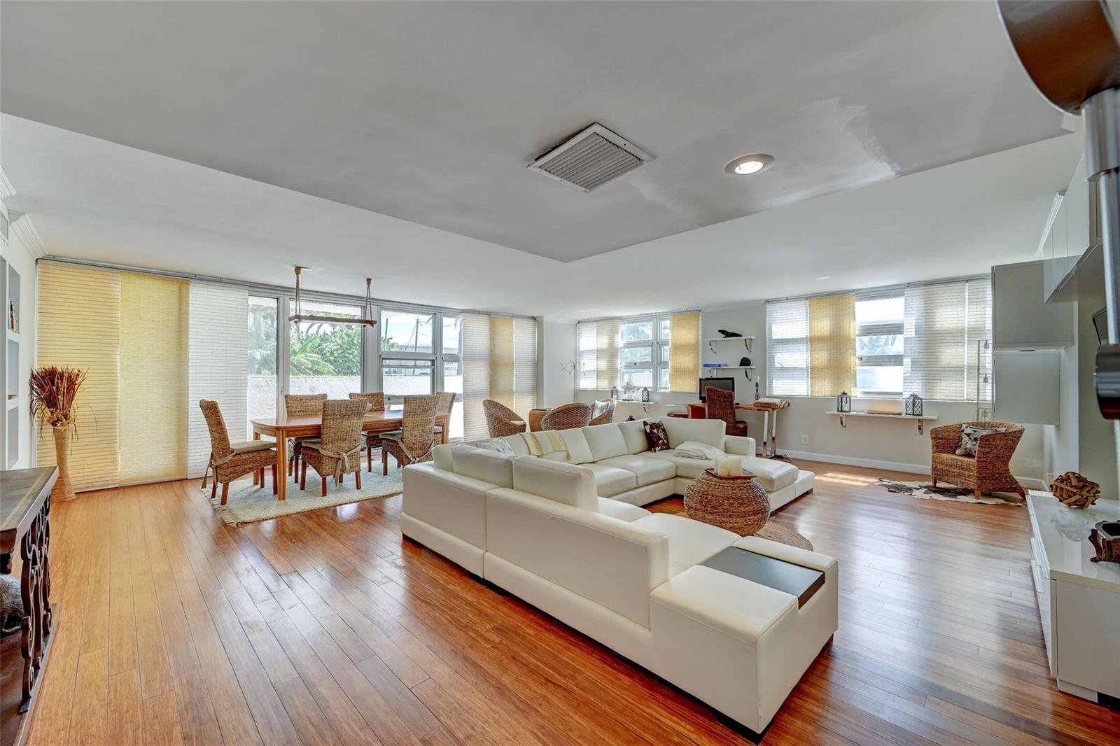 A spacious living and dining area features white leather sectional seating and hardwood flooring — 525 N Ocean Boulevard # 2, Pompano Beach FL 33062, POMPANO BEACH, FL