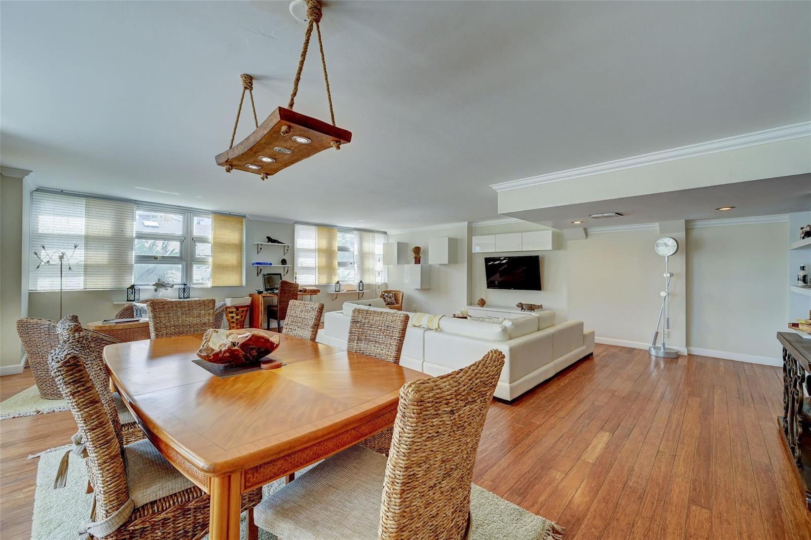 A dining area with a wooden table and wicker chairs opens into a living room — 525 N Ocean Boulevard # 2, Pompano Beach FL 33062, POMPANO BEACH, FL