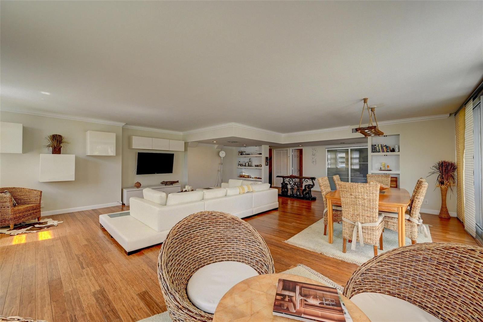 A spacious open-concept living and dining area features hardwood floors, wicker furniture, and white cabinetry — 525 N Ocean Boulevard # 2, Pompano Beach FL 33062, POMPANO BEACH, FL