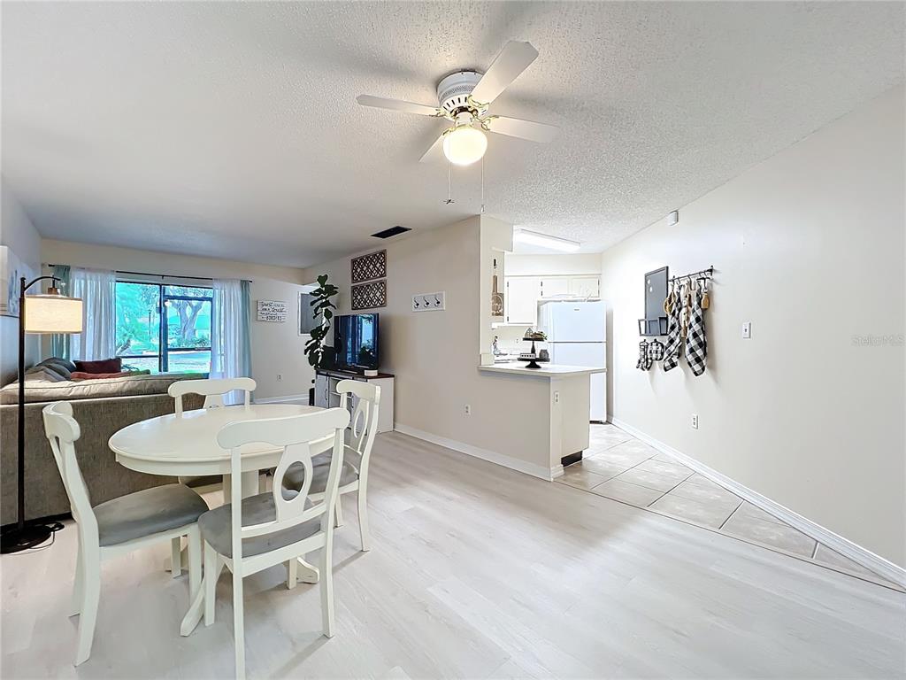 A dining area with a white table and chairs sits adjacent to an open kitchen — 3642 SOUTHPOINTE DRIVE UNIT L6, ORLANDO, FL