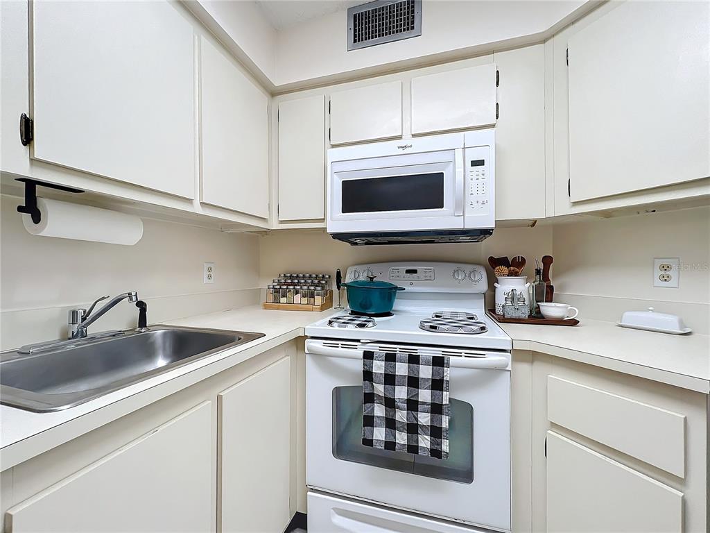 A kitchen features white cabinets, a stainless steel sink, and white appliances — 3642 SOUTHPOINTE DRIVE UNIT L6, ORLANDO, FL