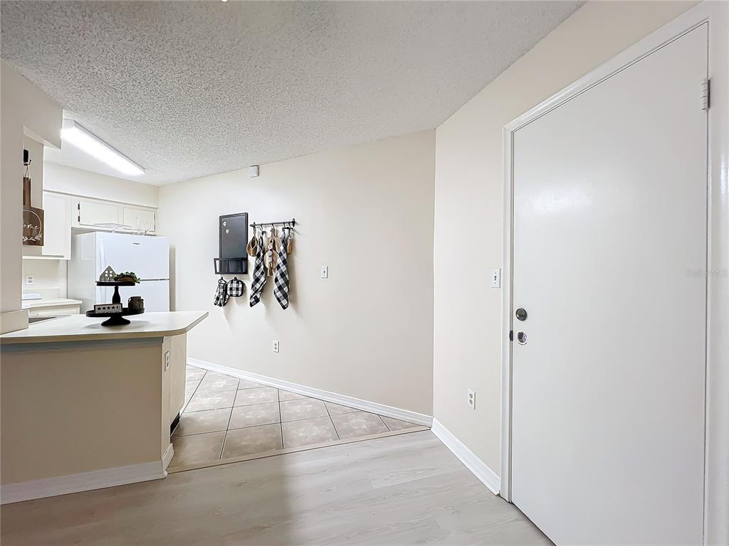 A kitchen with a breakfast bar, white appliances, and tile flooring adjacent to an entryway — 3642 SOUTHPOINTE DRIVE UNIT L6, ORLANDO, FL